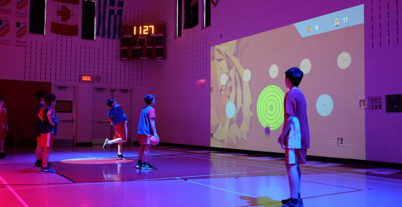 Children playing a video game projected on a wall