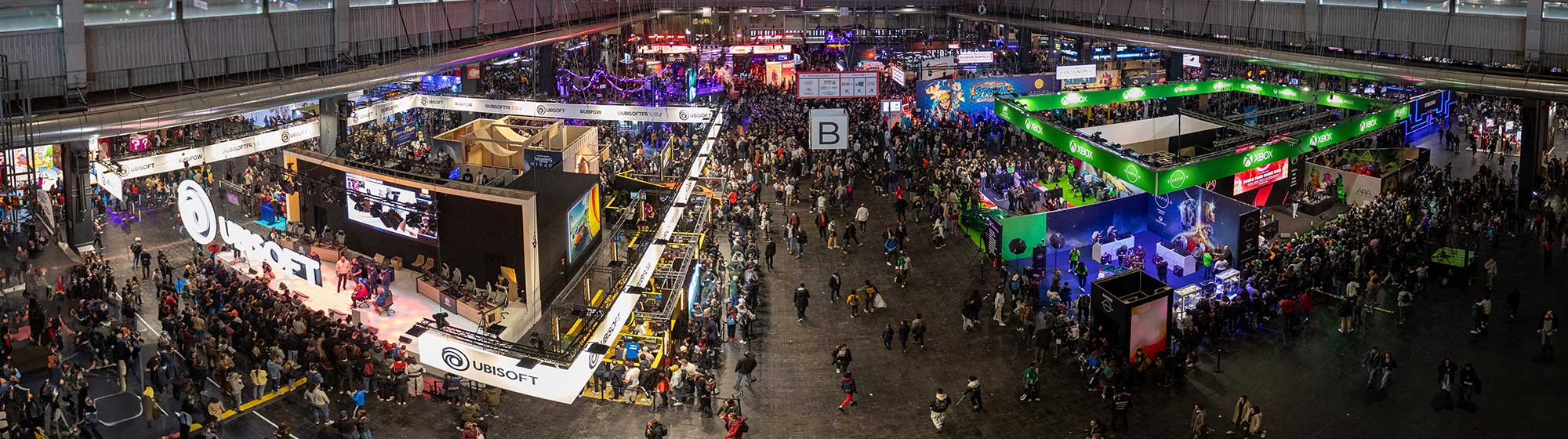 Panorma photo of Hall 1 at PGW 2023 with a crowd wandering between the ubisoft, xbox, Naruto Ninja Storm and Playstation stands.