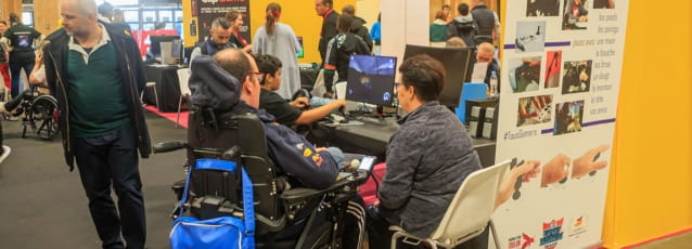 Personne handicapée jouant à un jeu vidéo avec quelques personnes autour d'elle