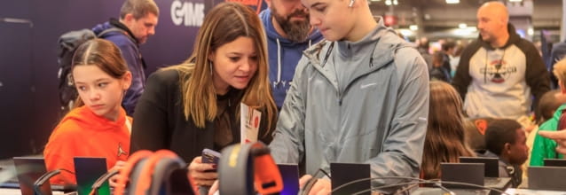 Young people and adults looking at electronic devices at Paris Games Week 2023