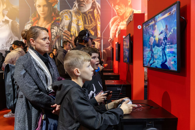 Parents and children sharing a moment together on the video game Tekken 8 at Paris Games Week 2023