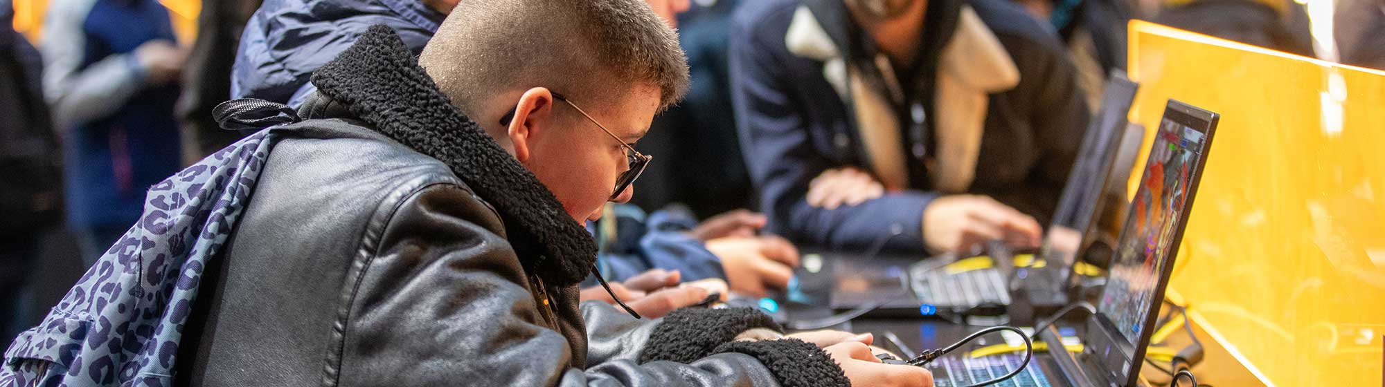 Enfants concentrés jouant à des jeux vidéo sur des ordinateurs portables avec un adulte en arrière-plan