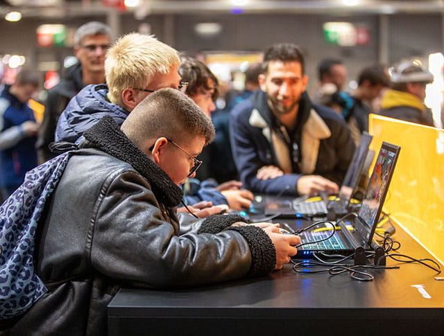Enfants concentrés jouant à des jeux vidéo sur des ordinateurs portables avec un adulte en arrière-plan