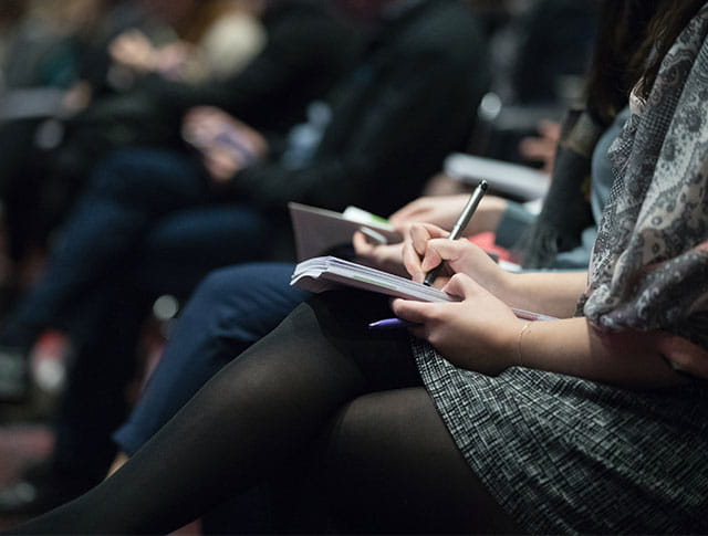 close-up of people writing in notebooks