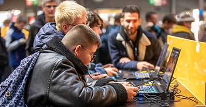 Enfants concentrés jouant à des jeux vidéo sur des ordinateurs portables avec un adulte en arrière-plan